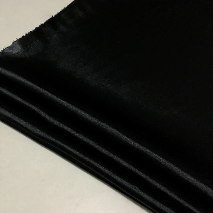 Gros plan sur le Tissu satin polyester uni au mètre de Longan Craft France, un tissu brillant et extensible idéal pour des vêtements ajustés et confortables, montrant sa texture lisse et son fini légèrement réfléchissant sur une surface claire.