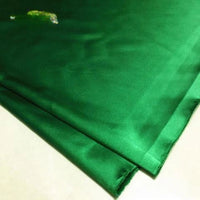 Gros plan sur deux pièces de Tissu satin polyester uni au mètre vert émeraude de Longan Craft France, dont la surface lisse et brillante est idéale pour les vêtements ajustés et confortables.