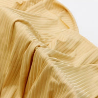 Gros plan sur le tissu côtelé en viscose mélangée jaune clair de Longan Craft France, caractérisé par des rayures verticales et des plis. Vendu au mètre, ce textile doux et extensible est idéal pour réaliser des t-shirts.
