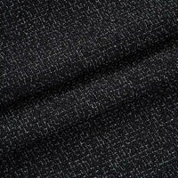 Gros plan sur le Tissu tweed uni au mètre de Longan Craft France : tweed de polyester noir avec des fils blancs visibles formant un motif texturé et quadrillé. Présenté plié, il est idéal pour les costumes et les vêtements chics.