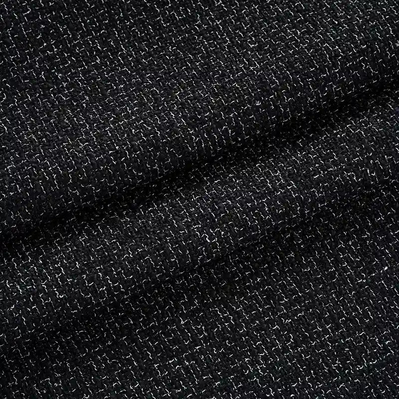 Une vue détaillée de Tissu tweed uni au mètre de Longan Craft France montre un tissu en polyester noir avec une texture tissée grossière et des fils blancs - idéal pour les costumes ou comme textile chic pour les vêtements.