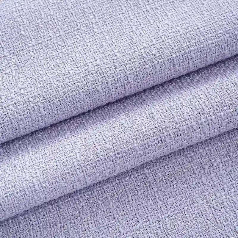 Gros plan sur le tissu tweed uni au mètre de Longan Craft France, un textile de polyester violet clair à la texture tissée chic et légèrement rugueuse, parfait pour les manteaux ou les costumes élégants.