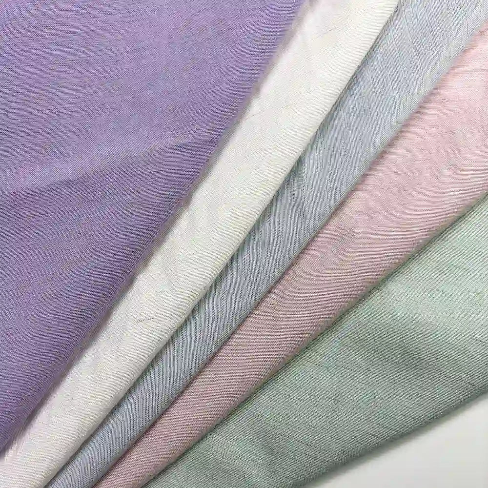 Quatre tissus pastel - lavande, blanc, rose pâle et vert pâle - sont disposés en diagonale. Le Tissu uni en viscose lyocell au mètre, lisse et respirant, de Longan Craft France, est parfait pour les peignoirs ou les chemises.