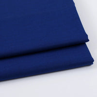 Deux pièces soigneusement pliées de gabardine uni au mètre de Longan Craft France - un mélange de laine, de rayonne et de polyester - empilées sur une surface blanche. Un textile idéal pour les vêtements décontractés et les blazers.