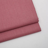 Deux pièces de tissu gabardine uni au mètre rose de Longan Craft France sont empilées sur une surface blanche. Cette gabardine sergée (laine/rayonne/polyester) lisse et unie est idéale pour les vêtements décontractés, les blazers et les vêtements sur mesure. Pas de motif visible.