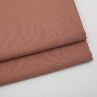 Deux pièces de Tissu gabardine uni de Longan Craft France, un mélange lisse de laine, de rayonne et de polyester, sont empilées sur une surface gris clair - un textile idéal pour les vêtements décontractés.