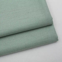 Gros plan sur deux pièces soigneusement pliées de Tissu gabardine uni au mètre de Longan Craft France, un mélange de laine, de rayonne et de polyester, idéal pour les tenues décontractées, empilées sur un fond clair.