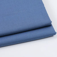 Gros plan sur deux Tissu gabardine uni au mètre de Longan Craft France, un mélange de gabardine sergée lisse et légèrement mate - idéal pour les tenues décontractées - empilés sur une surface blanche.