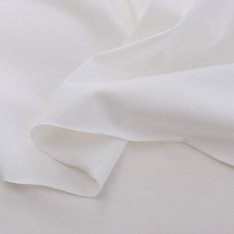 Gros plan sur le tissu jersey coton élasthanne au mètre de Longan Craft France, aux plis souples et à la texture lisse, idéal pour les peignoirs. Uni et extensible, ce jersey uni tissu est présenté sur un fond neutre.