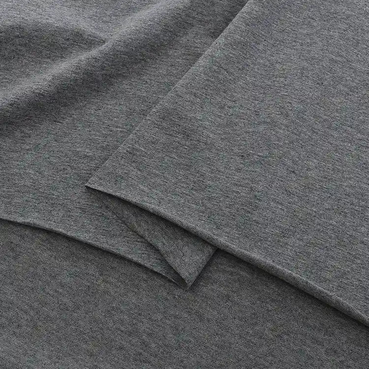 Gros plan sur le Jersey coton élasthanne uni de Longan Craft France, qui présente des couches douces et gris chiné de tissu jersey extensible, idéal pour les robes et vendu au mètre.