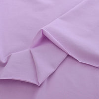 Un gros plan de Jersey coton élasthanne uni de Longan Craft France montre son tissu violet clair doux et lisse aux plis subtils - un tissu extensible aux couleurs uniformes, idéal pour les robes de chambre et les vêtements, disponible au mètre.