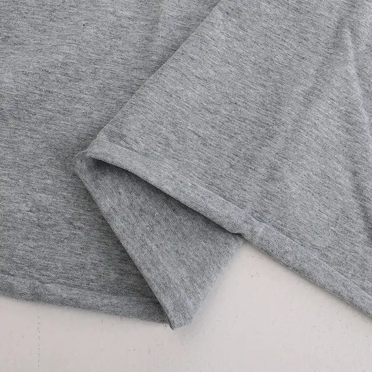 Gros plan sur le Jersey coton élasthanne au mètre de Longan Craft France, un tissu extensible gris clair montré à plat avec un ourlet et des coutures détaillés - parfait pour coudre des robes, des t-shirts et bien plus encore.