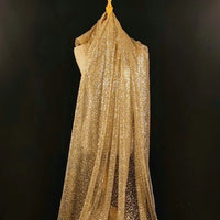 Un mannequin présente le tulle brodé de paillettes scintillantes de Longan Craft France, un tissu transparent et chatoyant pour robes de mariée, qui tombe en cascade sur un fond noir uni.