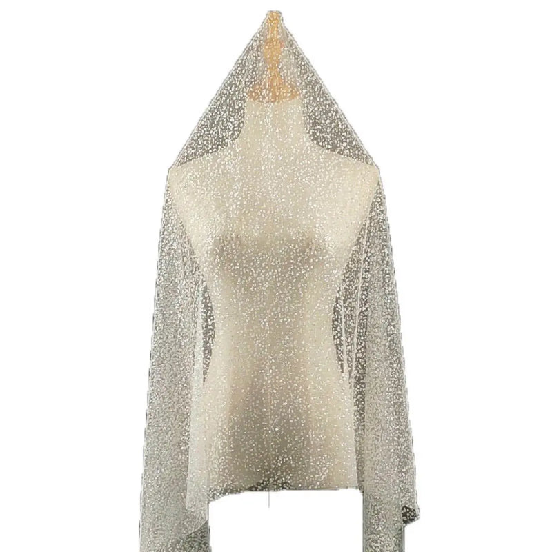 Un mannequin présente le tissu tulle brodé de paillettes scintillantes au mètre de Longan Craft France, un tulle de mariée chatoyant aux détails pailletés, élégamment drapé sur les épaules et descendant en cascade.