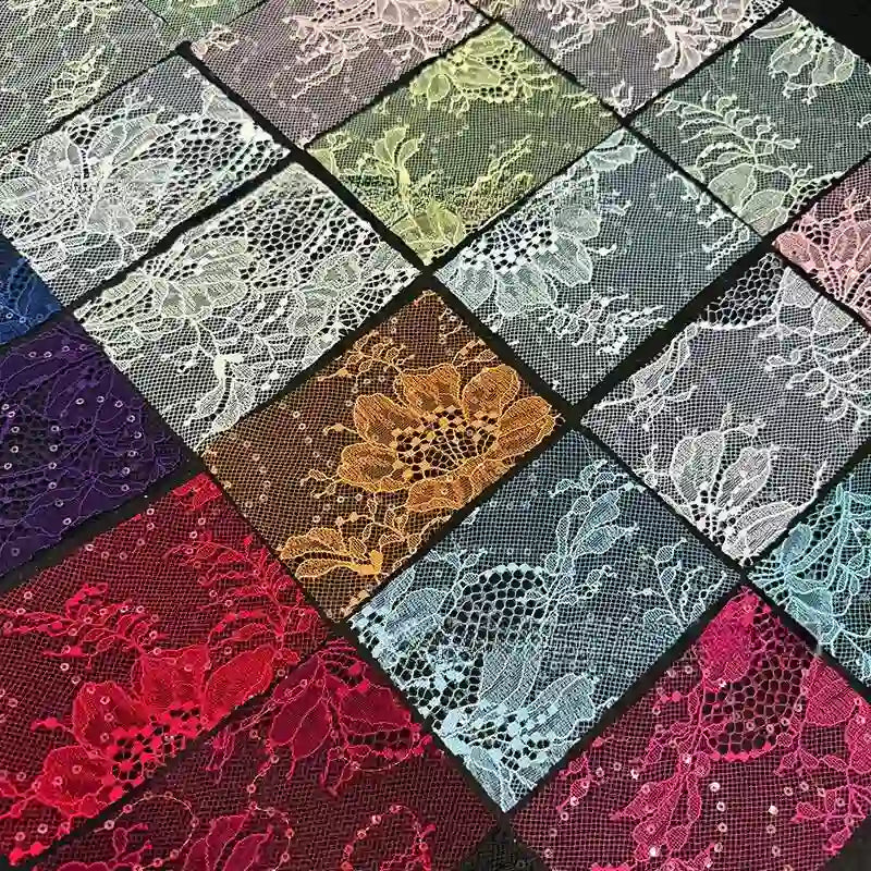 Des échantillons rectangulaires de Tissu dentelle pailleté avec sequins au mètre de Longan Craft France, dans les coloris rouge, blanc, jaune, violet, bleu, vert et rose, sont disposés dans une grille. Chacun d'entre eux présente des motifs floraux et une texture délicate en filet.
