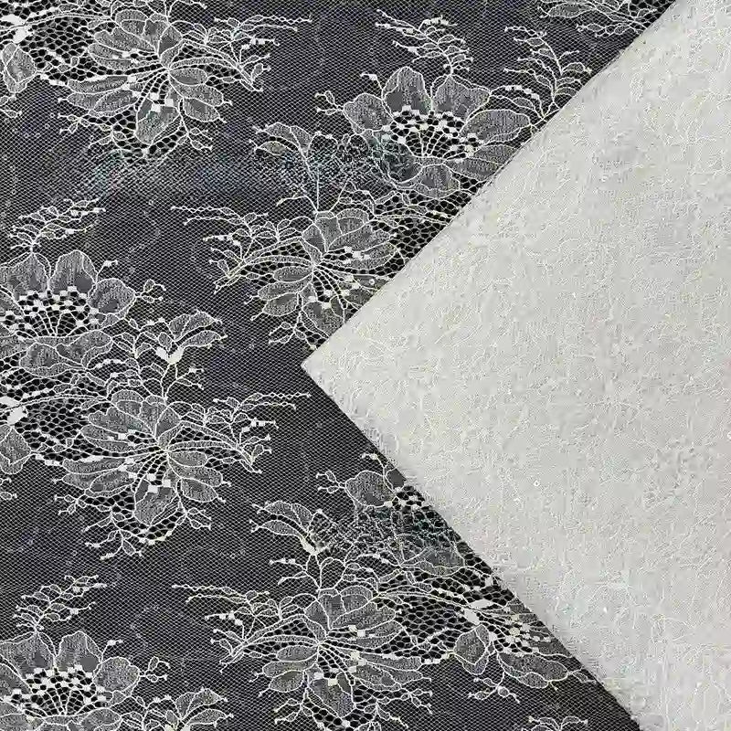 Gros plan sur deux tissus dentelle pailleté avec paillettes au mètre de Longan Craft France : une dentelle noire avec des motifs floraux blancs et une dentelle blanche unie, se chevauchant légèrement - idéal pour les robes élégantes ou les créations de lingerie.