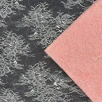 Une dentelle florale en maille noire avec broderie blanche se trouve à côté d'une dentelle pailletée rose unie, toutes deux issues du "Tissu dentelle pailleté avec paillettes au mètre" de Longan Craft France, disposées en angle pour la présentation.