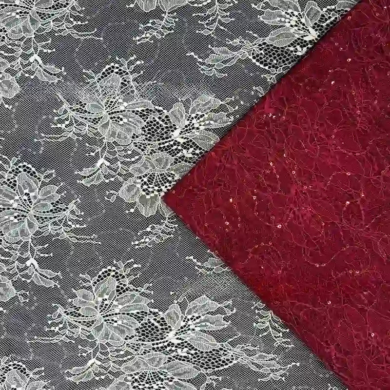 Gros plan sur deux tissus dentelle pailleté avec paillettes au mètre de Longan Craft France : l'un floral blanc sur maille noire, l'autre rouge avec un motif similaire, tous deux disposés en diagonale - parfaits pour les peignoirs et la lingerie.