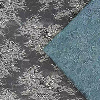 Un morceau blanc de tissu dentelle pailleté avec sequins de Longan Craft France est posé à plat, tandis qu'une variante bleu clair pliée lui est superposée. Les deux présentent des motifs floraux complexes, parfaits pour les peignoirs ou la lingerie.