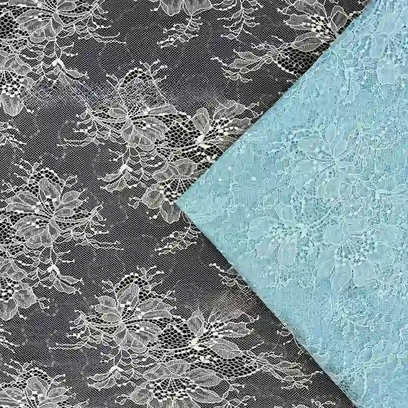 Deux Tissu dentelle pailleté avec sequins au mètre de Longan Craft France sont présentés : l'un noir avec broderie blanche, l'autre bleu clair. Les deux tissus sont des dentelles de qualité, parfaites pour les peignoirs ou la lingerie, disposées en biais l'une par rapport à l'autre.