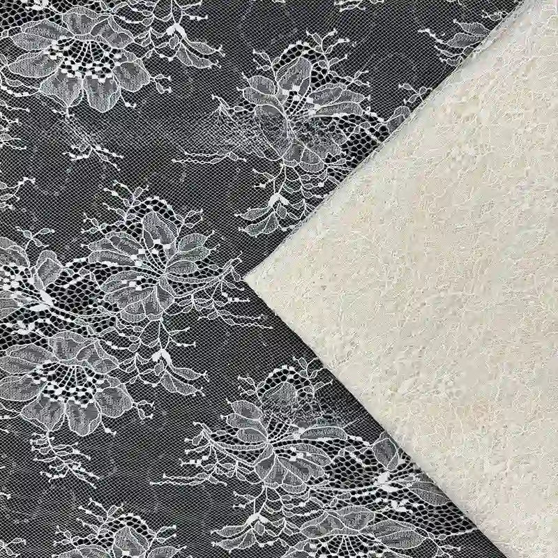 Gros plan sur deux tissus en dentelle : Tissu dentelle pailleté avec sequins au mètre de Longan Craft France, avec un motif floral, et une dentelle unie blanc cassé, les deux se chevauchant partiellement.