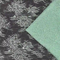 Un tissu dentelle pailleté avec sequins de Longan Craft France avec un motif floral blanc se trouve à côté d'un tissu dentelle vert menthe plié pour robe, tous deux présentés à plat.