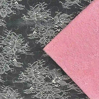Un étincelant "Tissu dentelle pailleté avec paillettes au mètre" de Longan Craft France repose sur une dentelle florale noire. Le luxueux tissu dentelle noir pour robes domine l'image et la dentelle rose se trouve dans le coin supérieur droit.