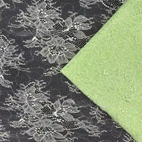 Un morceau de Longan Craft France Tissu dentelle pailleté avec sequins au mètre superpose de la dentelle noire avec des motifs floraux blancs, soulignant la qualité et le détail - idéal tissu dentelle pour robes et lingerie.