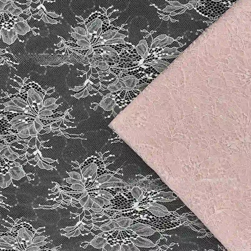 Un tissu en maille noire avec une dentelle florale blanche est partiellement recouvert par le Tissu dentelle pailleté avec sequins au mètre de Longan Craft France, une dentelle à paillettes rose pâle, tous deux montrés à plat depuis le dessus.