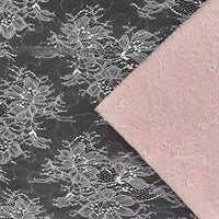 Un tissu en maille noire avec une dentelle florale blanche est partiellement recouvert par le Tissu dentelle pailleté avec sequins au mètre de Longan Craft France, une dentelle à paillettes rose pâle, tous deux montrés à plat depuis le dessus.