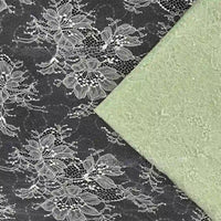 Le tissu dentelle vert pâle pailleté avec paillettes de Longan Craft France est superposé à de la dentelle noire ornée de fleurs blanches audacieuses et d'un motif floral subtil - idéal tissu dentelle pour robes et lingerie.