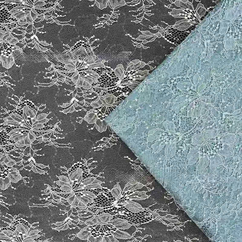 Gros plan sur deux pièces de Tissu dentelle pailleté avec sequins au mètre de Longan Craft France - l'une noire avec des fleurs blanches, l'autre bleu clair - dentelle de qualité idéale pour les peignoirs, la lingerie ou les projets créatifs.