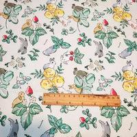 Le motif en tissu Pâques lapin de printemps de Longan Craft France représente des lapins colorés, des fleurs jaunes, des fraises et des feuilles vertes. Une règle en bois en bas au centre indique l'échelle. Coton doux parfait pour créations printanières.