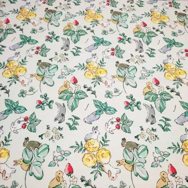 Le Tissu motif Pâques lapin de printemps de Longan Craft France est un coton doux et coloré avec des fleurs jaunes, des feuilles vertes, des fraises et des lapins espiègles sur un fond blanc - idéal pour la décoration et l'artisanat de printemps.