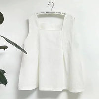 Le Patron de couture gratuit pour blouse sans manches à encolure carrée de Longan Craft France, un patron PDF facile pour débutants, est suspendu sur un cintre blanc avec quelques feuilles vertes visibles à gauche.