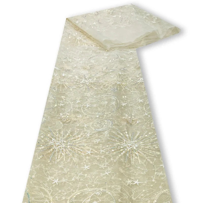 Le tulle brodé de sequins étoiles et lunes au mètre de Longan Craft France est un tissu transparent beige clair brodé de sequins blancs et argentés, parfait pour les robes. Présenté sur un fond blanc.