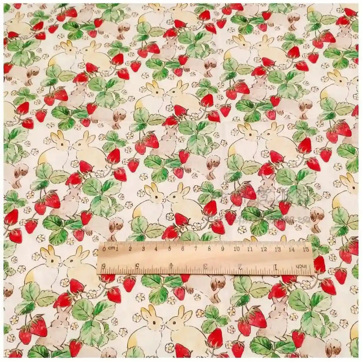 Le tissu motif Pâques lapin et fraises de Longan Craft France, 100 % coton doux, présente des lapins blancs, fraises rouges et feuilles vertes. Un mètre en bois est posé horizontalement en bas pour l'échelle.