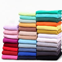 Trois piles de Tissu French Terry en coton extensible de Longan Craft France sont soigneusement disposées sur un fond blanc - confortable, multicolore et idéal pour les vêtements de sport, vendus au mètre.