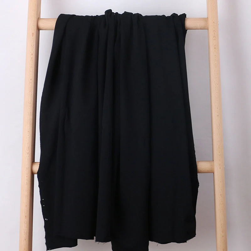 A Tissu French Terry en coton extensible au mètre de Longan Craft France, idéal pour vêtements de sport, est drapé sur une échelle en bois clair devant un fond blanc.