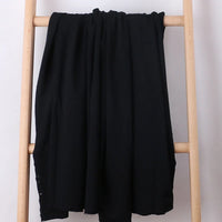 A Tissu French Terry en coton extensible au mètre de Longan Craft France, idéal pour vêtements de sport, est drapé sur une échelle en bois clair devant un fond blanc.