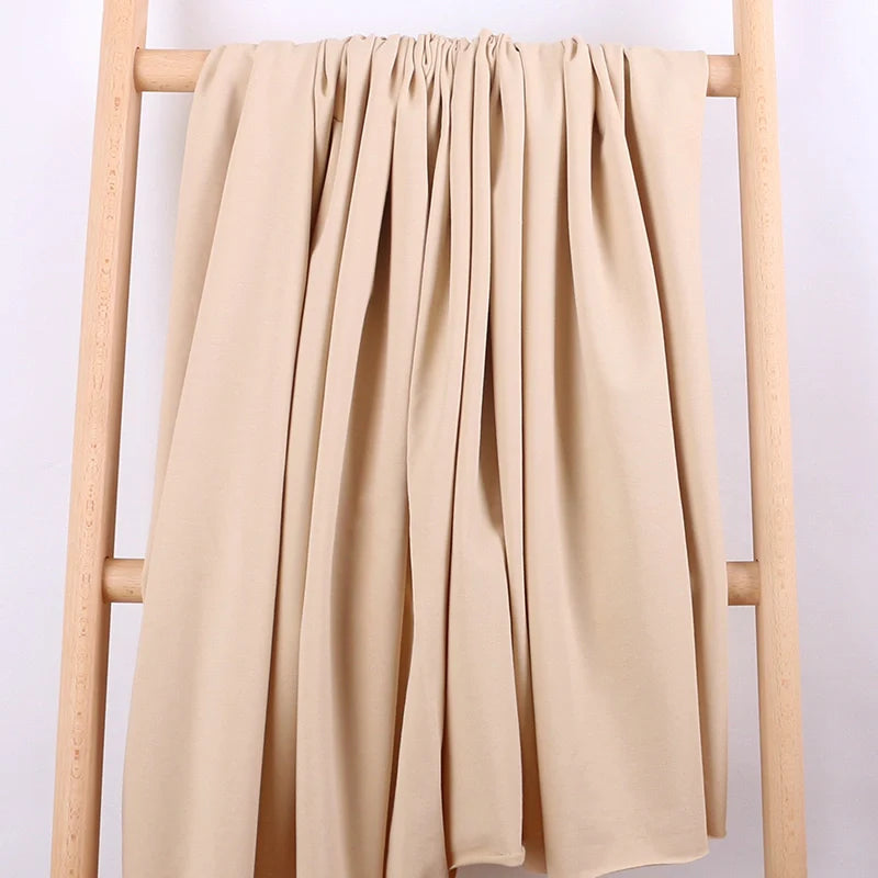 Le Tissu French Terry en coton extensible au mètre de Longan Craft France, idéal pour vêtements de sport, est drapé sur une échelle en bois clair devant un fond blanc, mettant en valeur sa douceur et son tombé parfait pour sweatshirts.