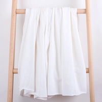 Un morceau de Tissu French Terry en coton extensible de Longan Craft France est drapé sur les barreaux centraux d'une échelle en bois clair, sur un fond blanc uni. Ce tissu confortable et multicolore est idéal pour les vêtements de sport.