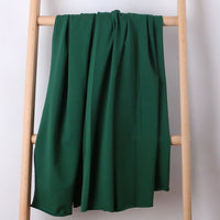 Une longueur de tissu French Terry multicolore en coton extensible de Longan Craft France est drapée sur une échelle en bois clair sur un fond blanc uni, montrant sa texture confortable, idéale pour les vêtements de sport.