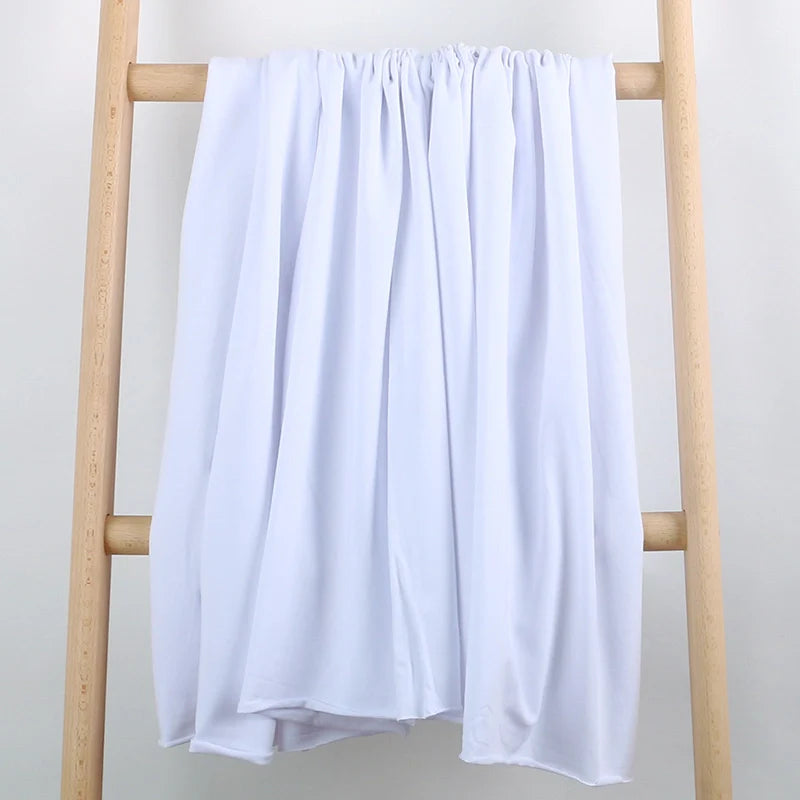 Un tissu extensible en coton French Terry multicolore de Longan Craft France se drape sur une échelle en bois clair, sur fond blanc. Idéal pour les vêtements de sport et vendu au mètre.