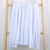 Un tissu extensible en coton French Terry multicolore de Longan Craft France se drape sur une échelle en bois clair, sur fond blanc. Idéal pour les vêtements de sport et vendu au mètre.