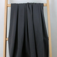 Un tissu multicolore et confortable en coton extensible French Terry de Longan Craft France est drapé sur une échelle en bois clair sur un fond blanc uni - idéal pour les vêtements de sport et vendu au mètre.