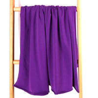 Un morceau de Tissu French Terry en coton extensible au mètre de Longan Craft France, confortable et multicolore, idéal pour les vêtements de sport, est drapé sur une échelle en bois sur fond blanc.