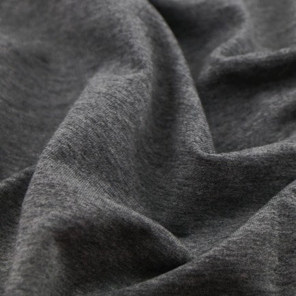 Gros plan sur un tissu multicolore, doux et extensible en coton French Terry de Longan Craft France, idéal pour les vêtements de sport. Tissu French Terry en coton extensible au mètre, montrant texture et plis confortables.