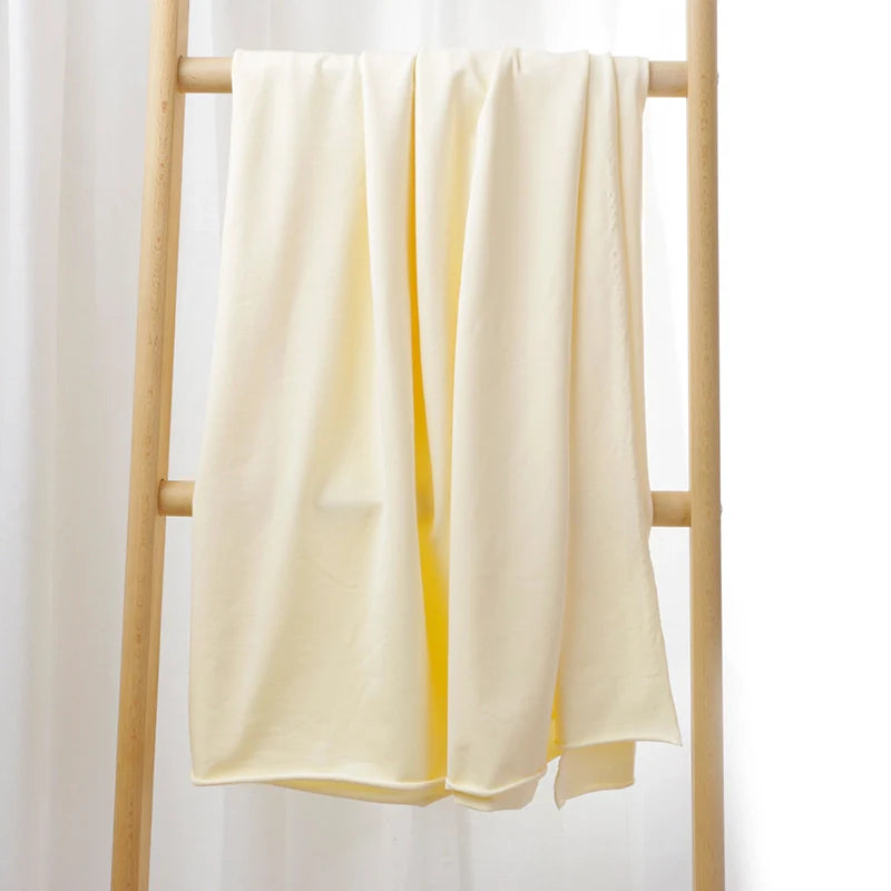 Le Tissu French Terry en coton extensible au mètre de Longan Craft France, drapé sur une échelle en bois devant un rideau blanc, met en valeur son confort et ses motifs multicolores, parfait pour des vêtements de sport.