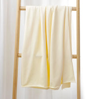 Le Tissu French Terry en coton extensible au mètre de Longan Craft France, drapé sur une échelle en bois devant un rideau blanc, met en valeur son confort et ses motifs multicolores, parfait pour des vêtements de sport.